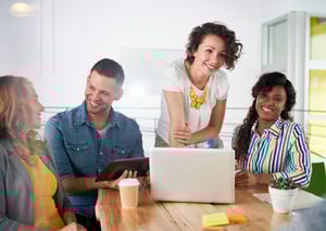 Multiethnic group of succesful creative business people using a laptop during candid meeting